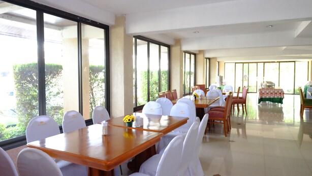 A conference room with large windows, white chairs, and a wooden table. - PC Palace Hotel (Sakon Nakhon)