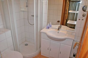 Ett badrum med dusch, toalett, handfat och skåp.
