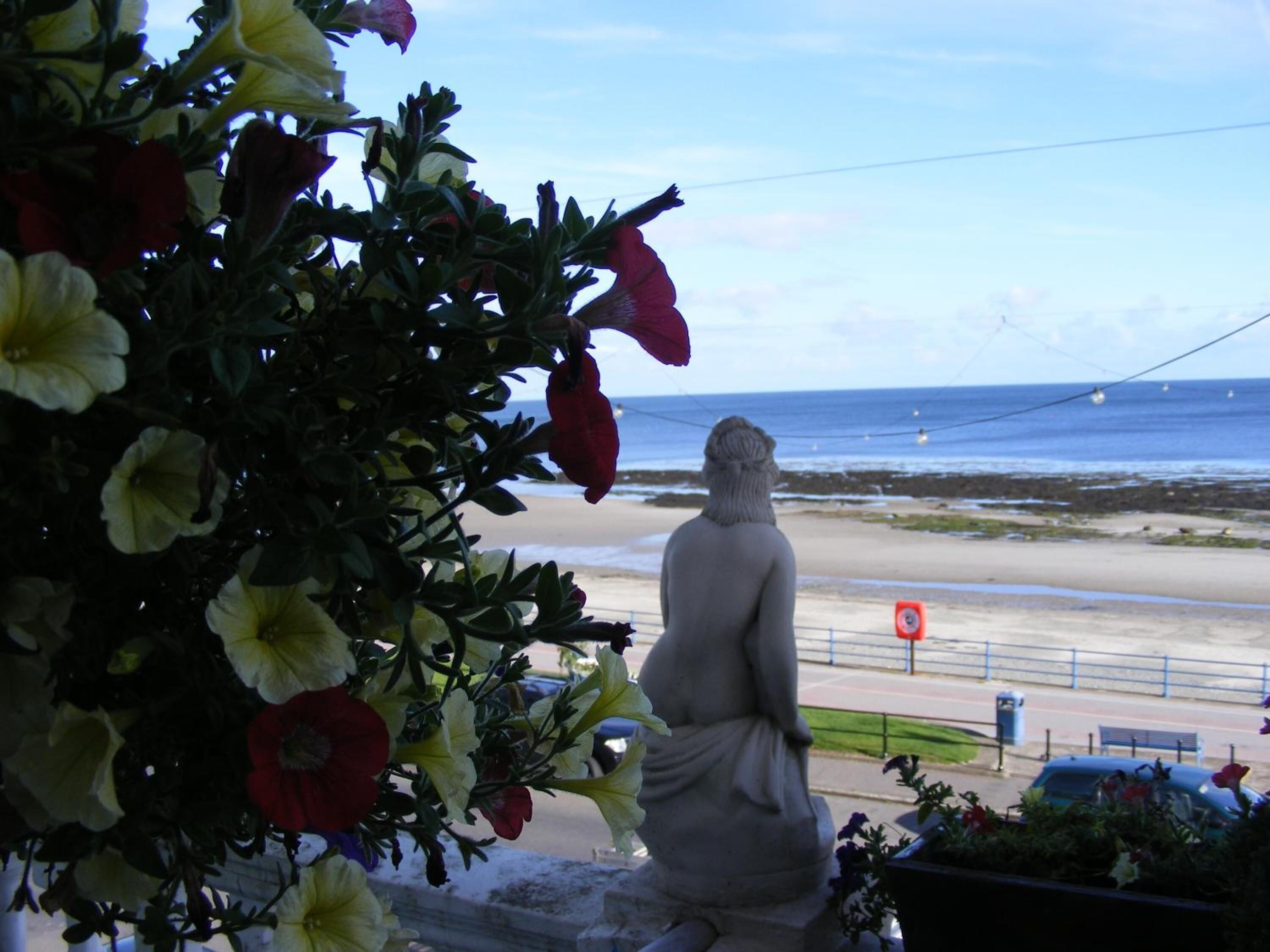 A statue overlooking a beach with a clear view of the ocean.