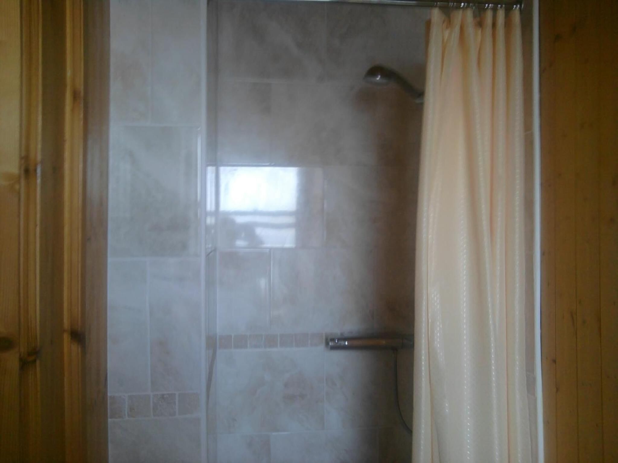 A shower with a glass door, a metal handle, and a curtain.