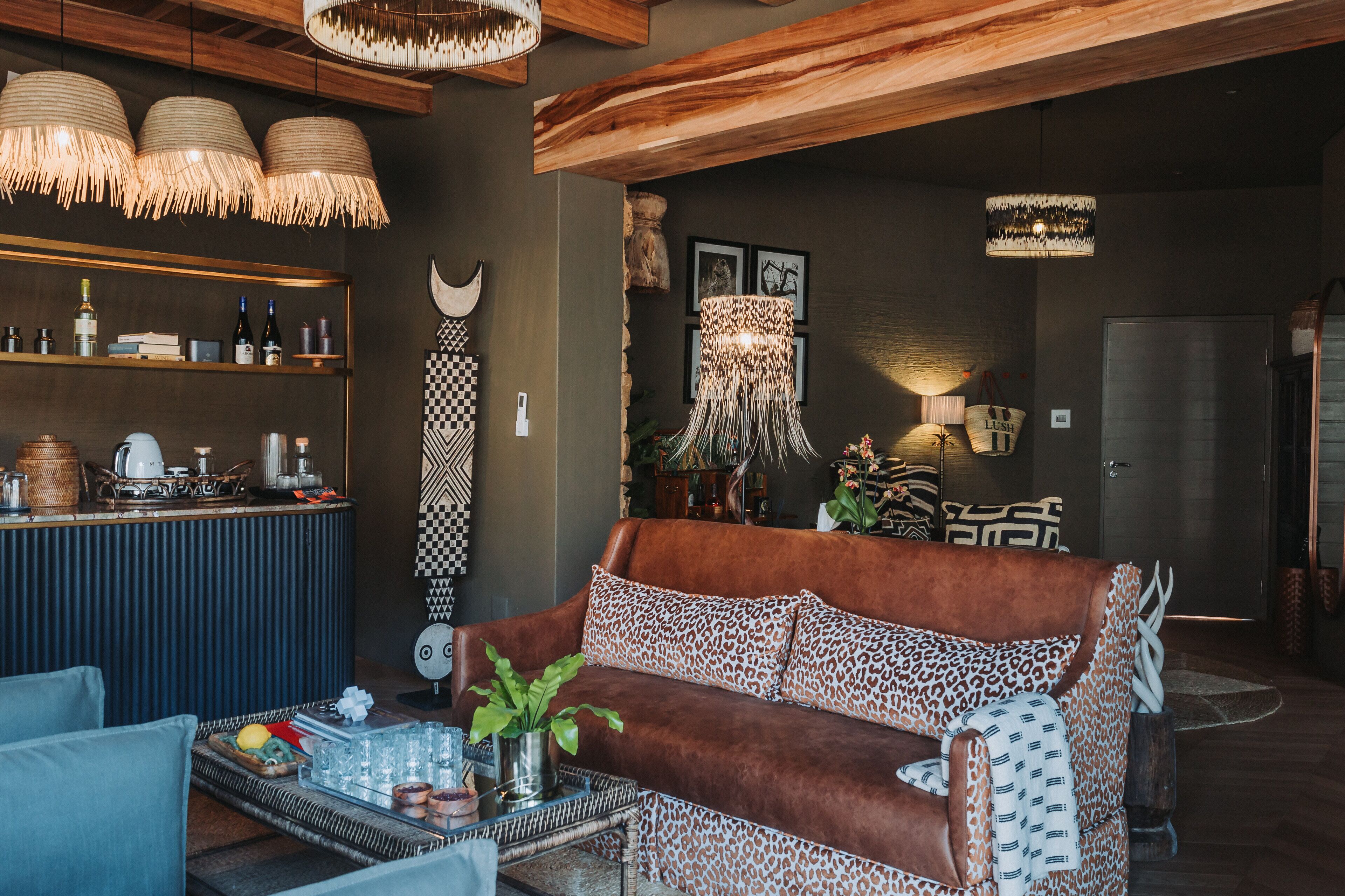 Una sala de estar acogedora con un sofá marrón, una mesa de centro con bebidas y una zona de bar con botellas y vasos.