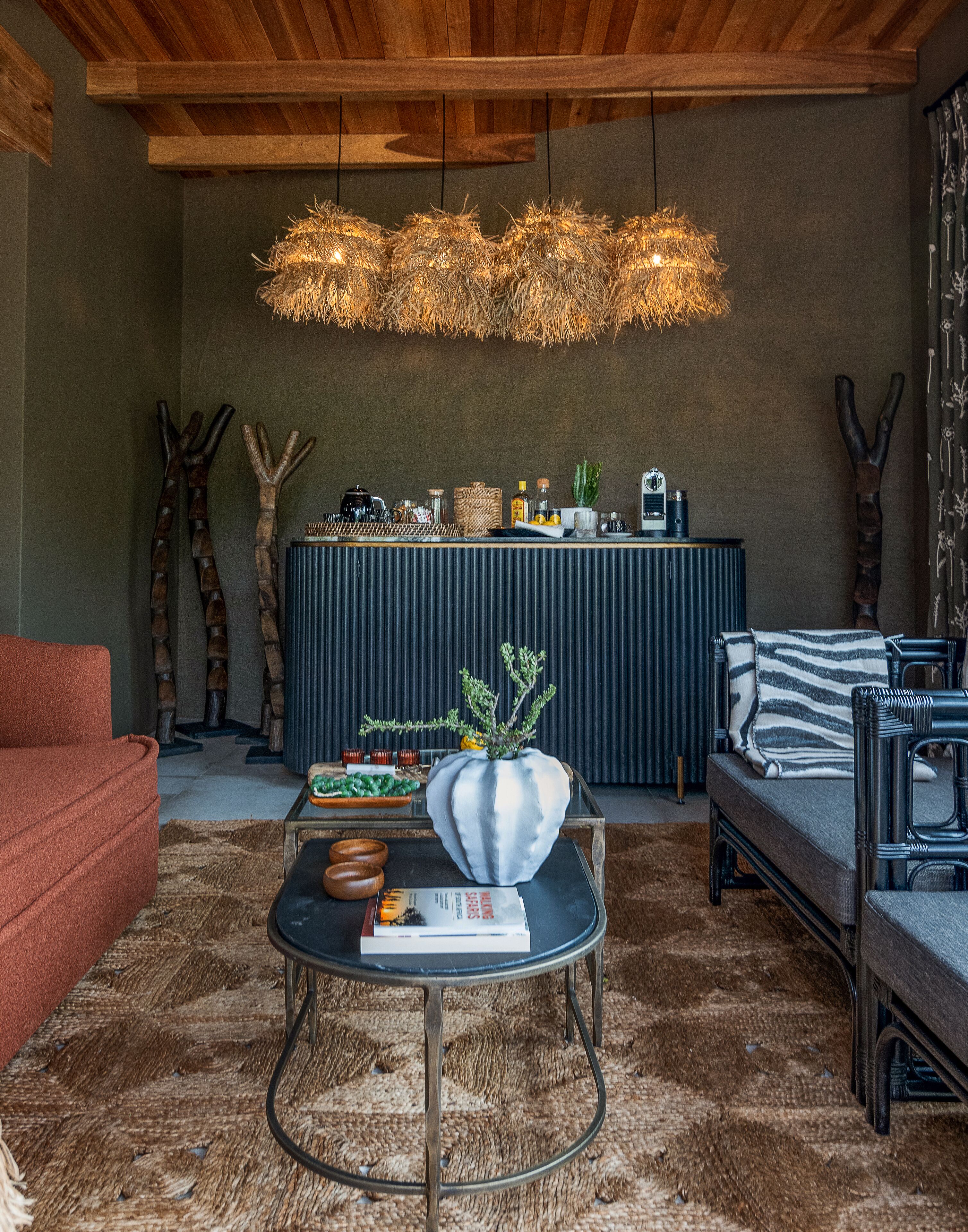 Una sala de estar moderna con techo de madera, una mesa redonda para café, un sofá y una planta decorativa.