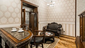 Un área de comedor con una mesa de mármol, sillas y una taza de café. Hay un sofá de cuero y una alfombra estampada en el suelo.