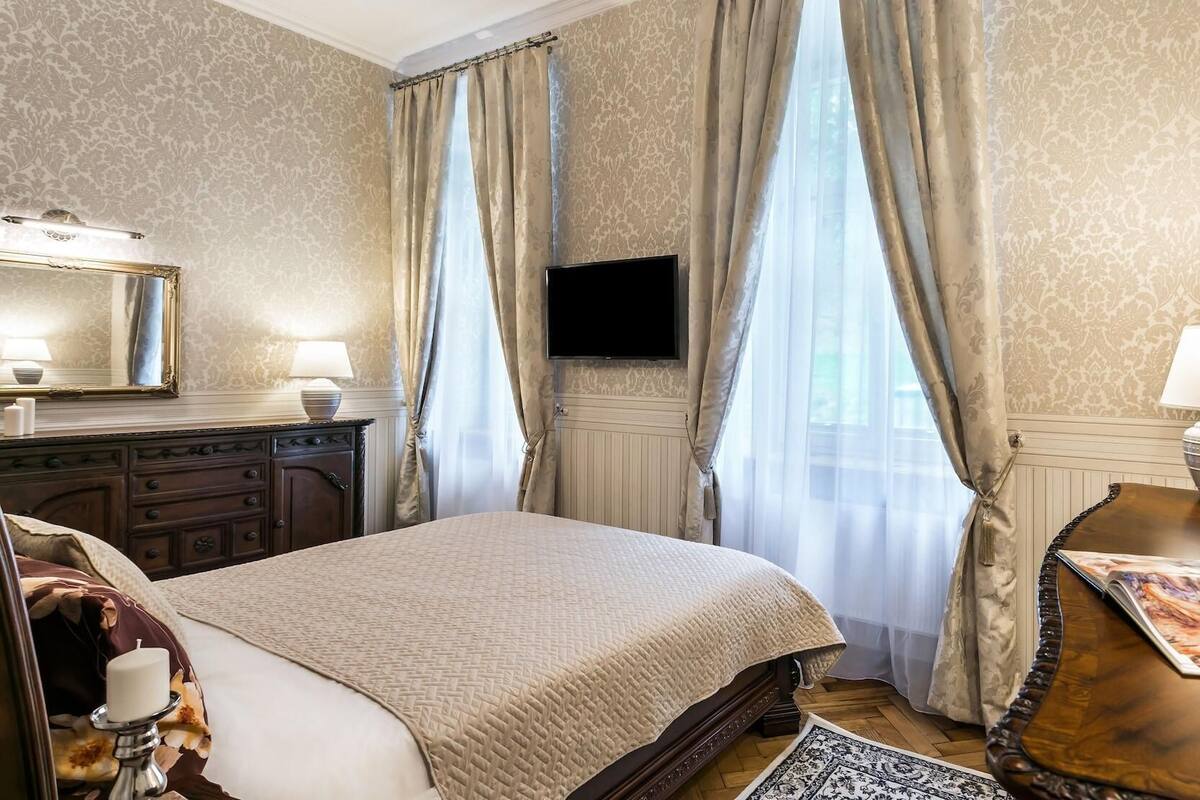 A hotel room with a bed, a dresser, a flat-screen TV, and a painting on the wall.