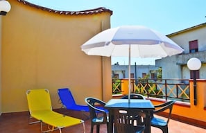 A terrace with a table and chairs, a white umbrella, and two colorful lounge chairs. - Villa Paeonia (Capaccio-Paestum)