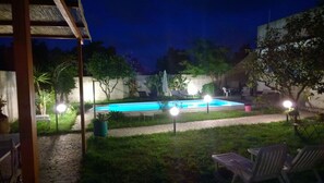 A swimming pool with surrounding greenery and a covered seating area. - B&B Villa Romina (Lecce)