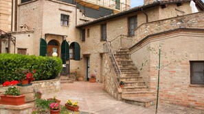 A traditional stone building with a courtyard, a staircase, and potted plants. - Il Pozzo di Sant'Andrea (Siena)