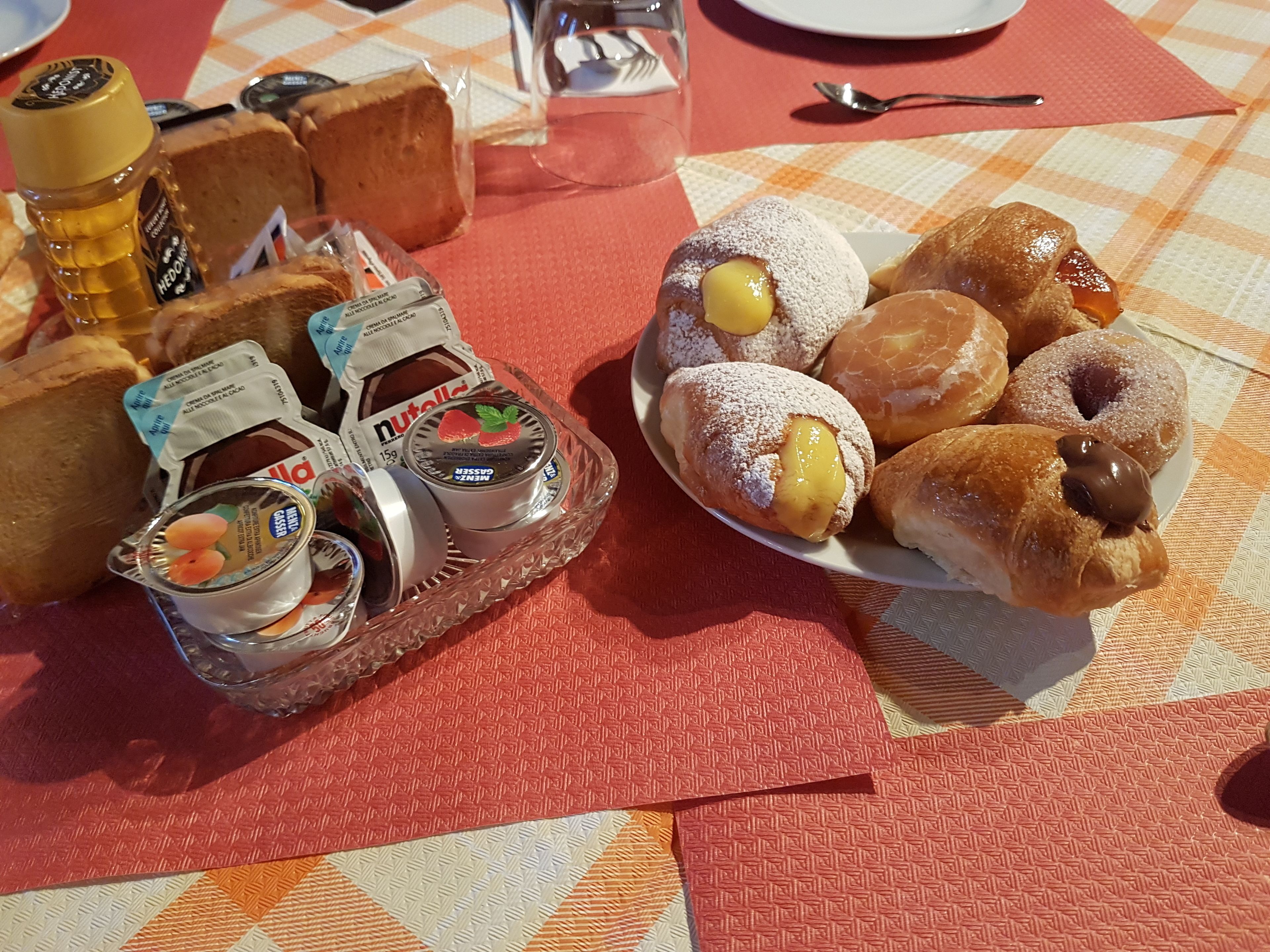 A table with a variety of food items including bread, pastries, and condiments.