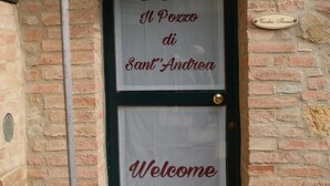 Une porte sur laquelle est affiché un panneau indiquant « B&B Il Pozzo di Sant'Andrea » et, en dessous, le mot « Bienvenue ».