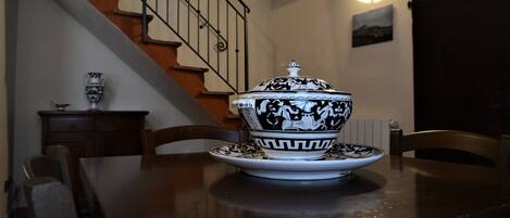Una mesa de comedor con un cuenco decorativo y un plato, una silla y una escalera al fondo.
