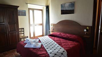 A bedroom with a large bed, a wooden wardrobe, and a door leading to an outdoor area.