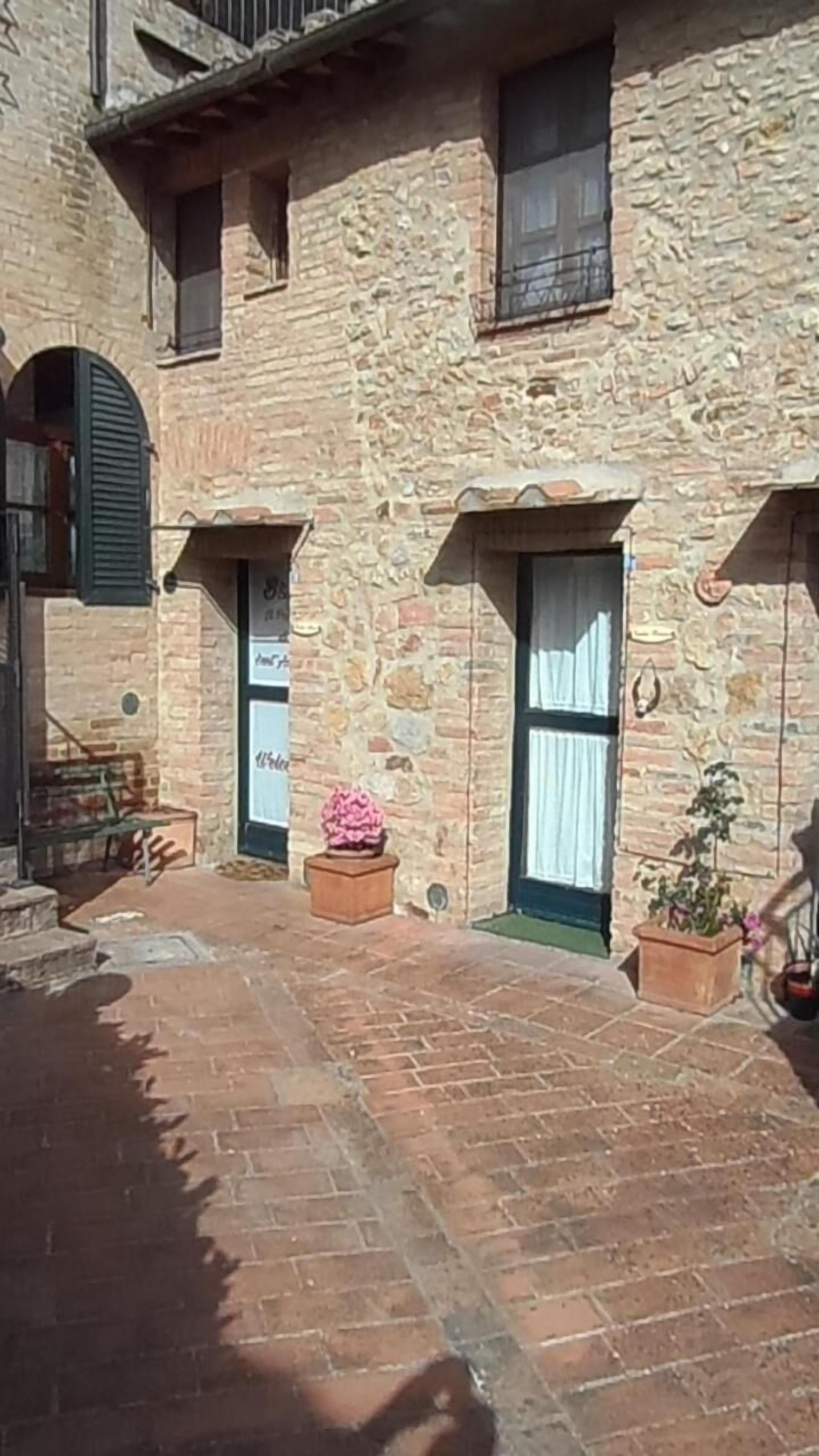 Un bâtiment en pierre doté de fenêtres en arc de cercle et d’une cour pavée de briques.