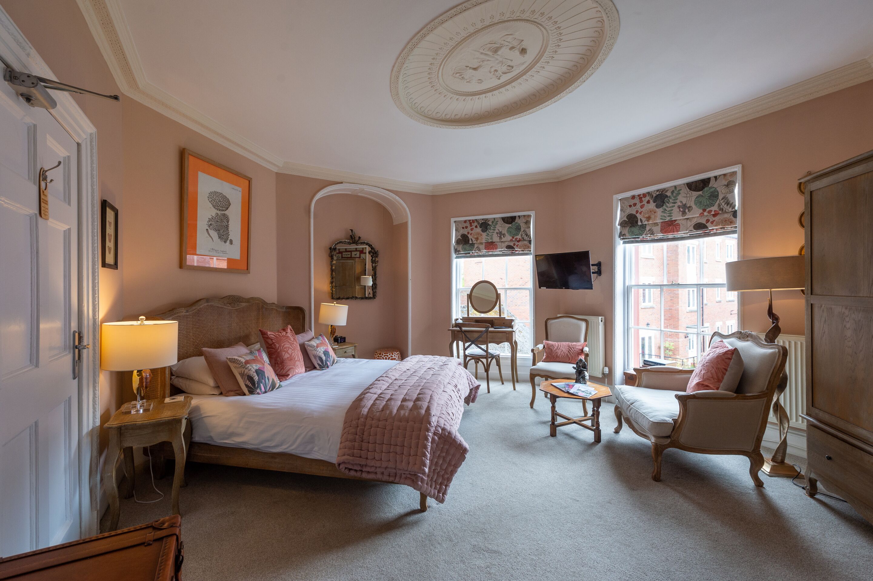 A bedroom with a large bed, two chairs, a desk, and a dresser.