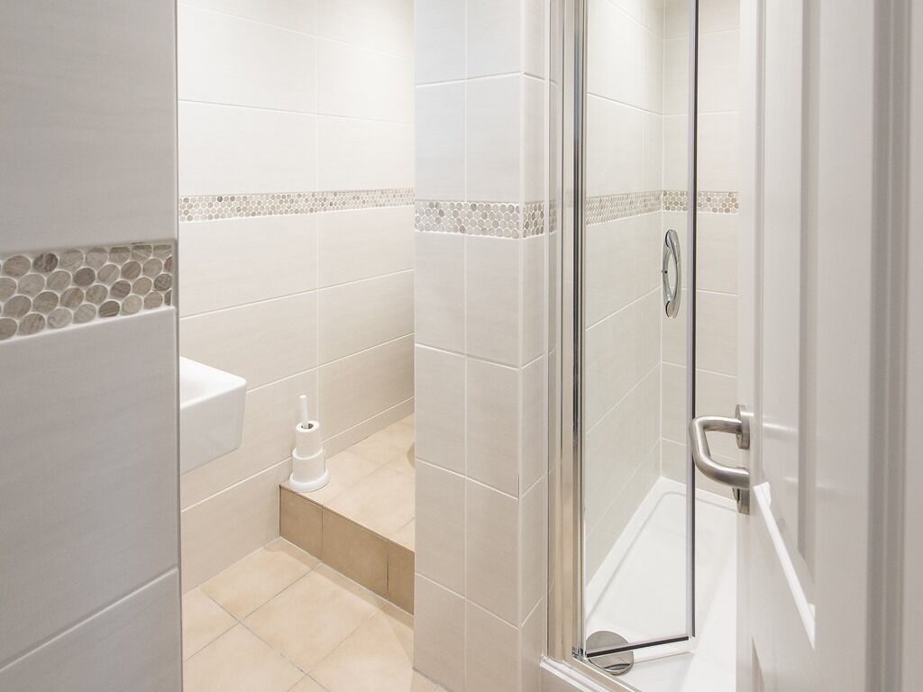 A modern bathroom with a glass shower enclosure, a toilet, and a bidet.