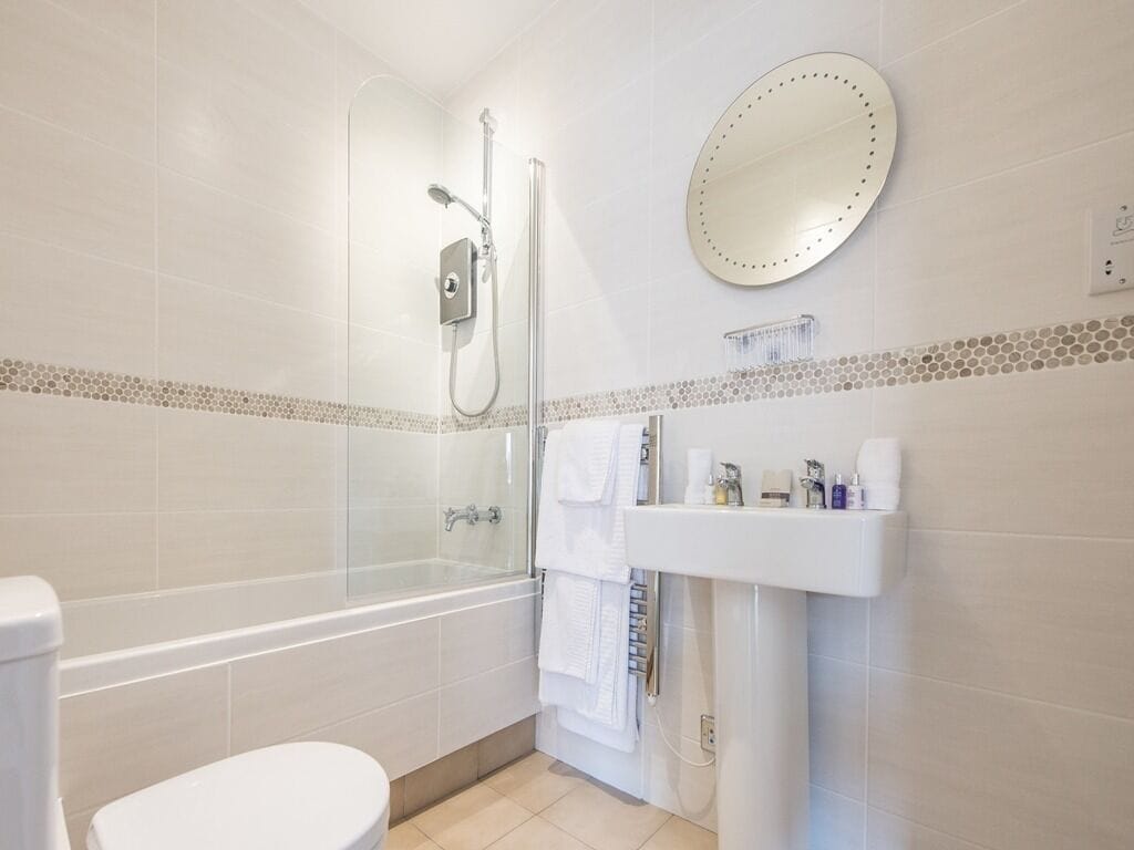 A modern bathroom with a bathtub, shower, and toilet.