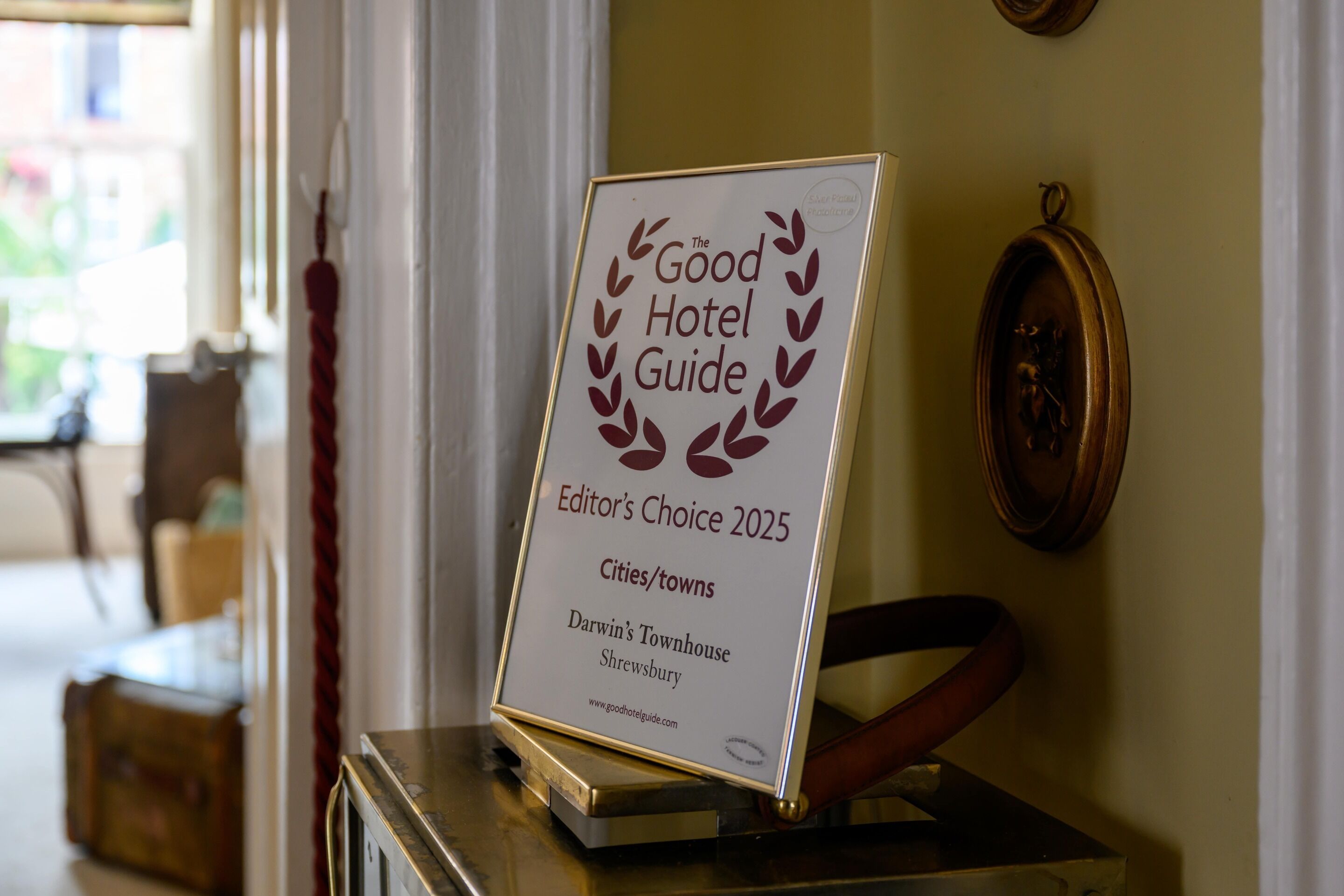 A framed award plaque for 'The Good Hotel Guide Editor's Choice 2025' placed on a table.