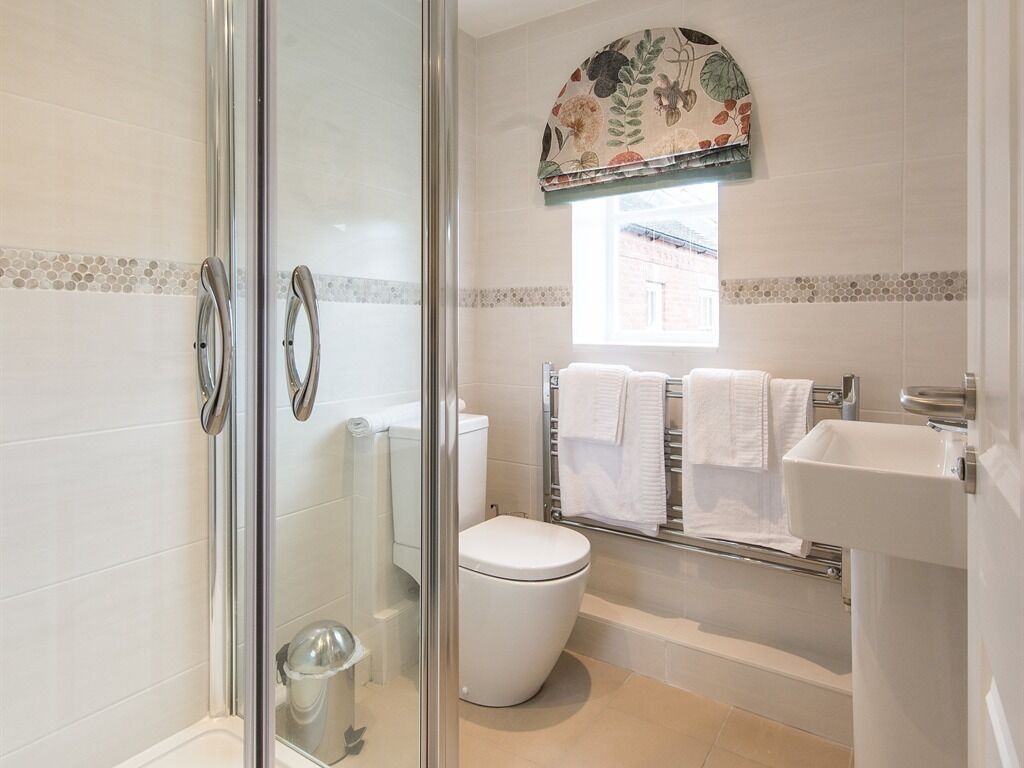 A bathroom with a glass shower enclosure, a toilet, a bathtub, and a sink.