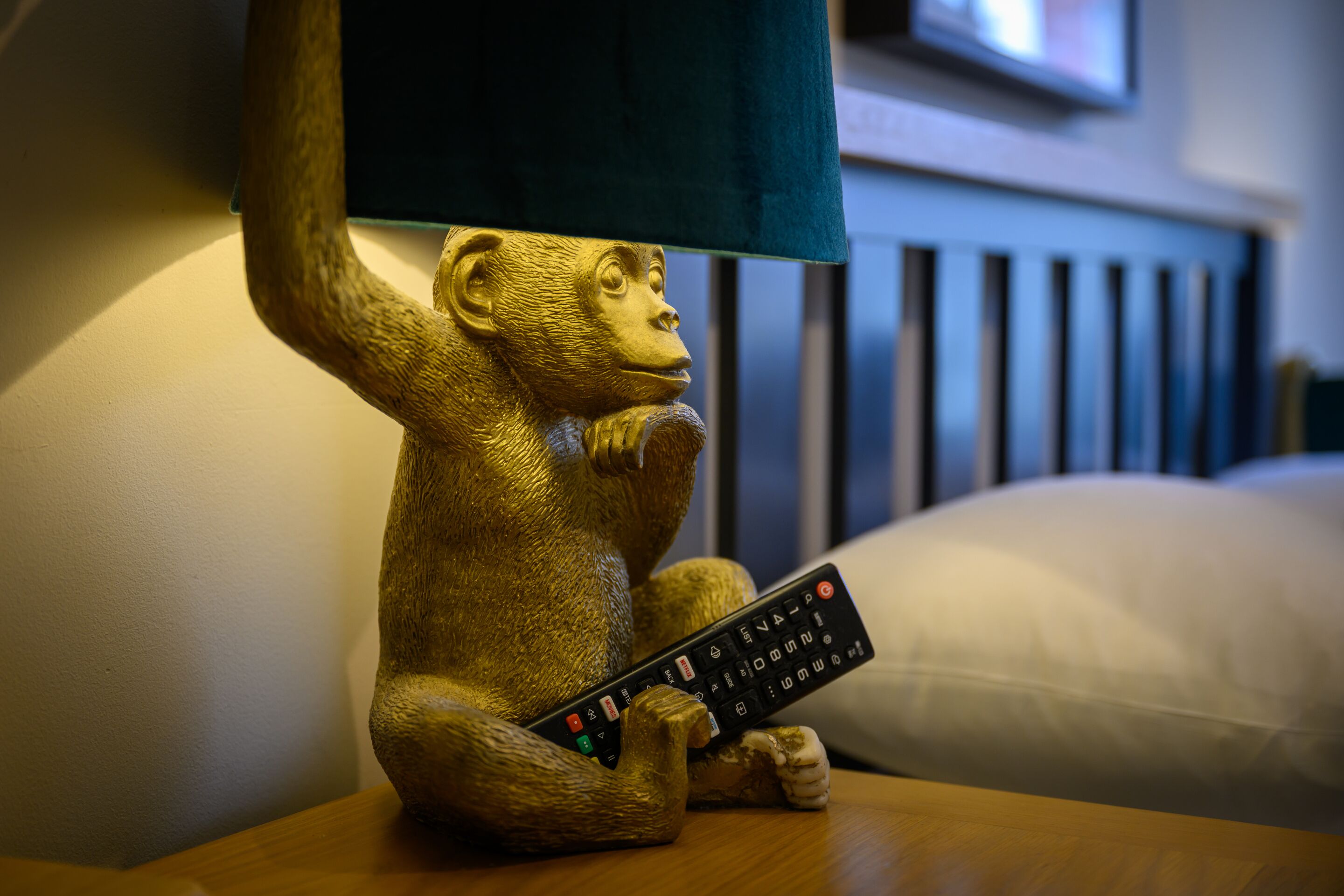 Una figurita dorada de un mono sosteniendo un control remoto.