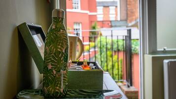 A green water bottle with a leaf pattern on a table with a picture frame and a green box.