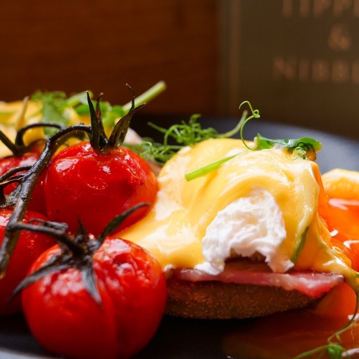 A plate with a sandwich, tomatoes, and a garnish.