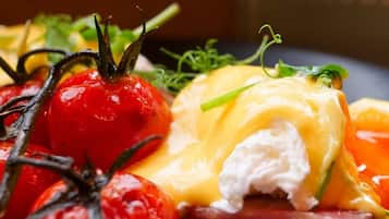 A plate with a sandwich, tomatoes, and a garnish.