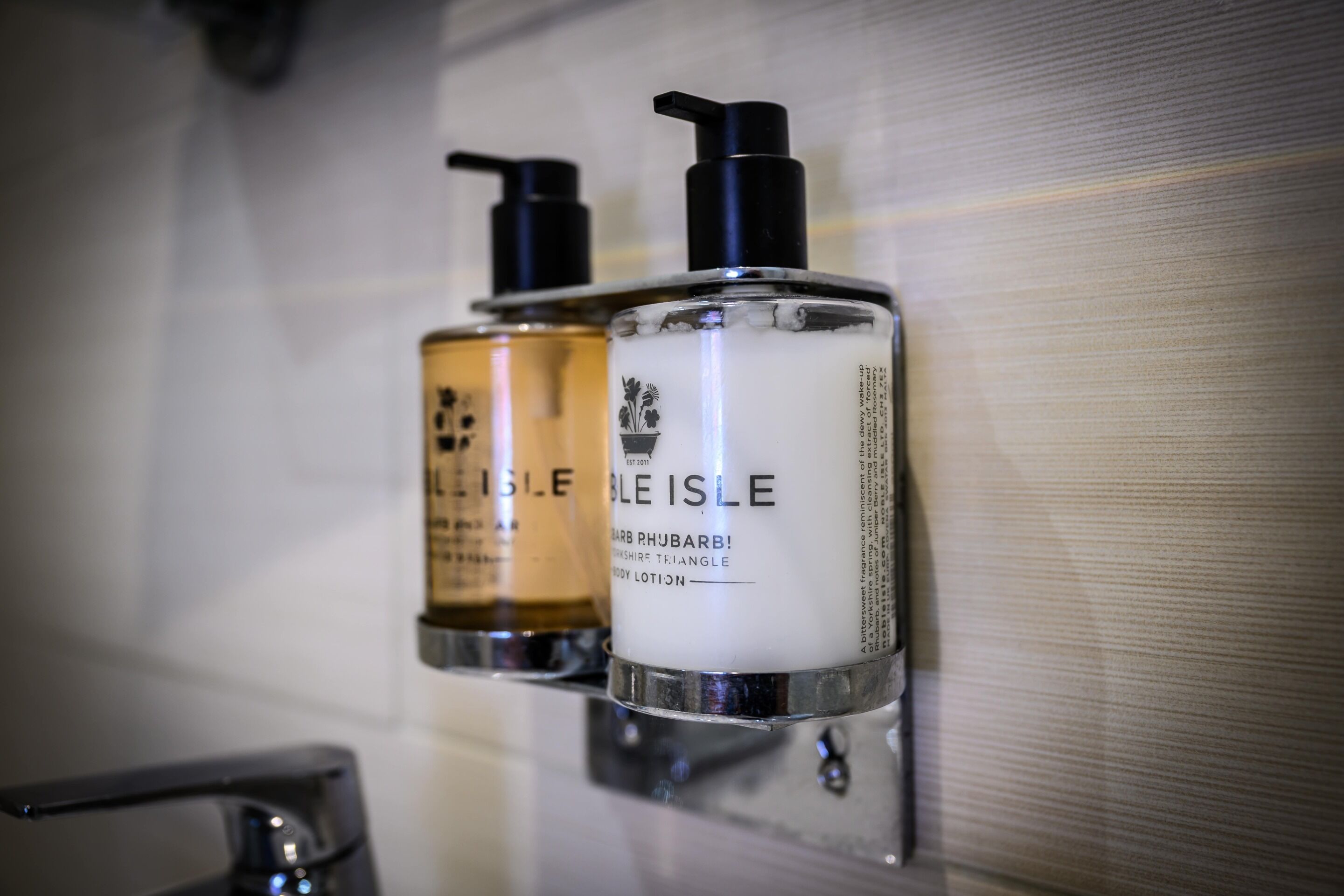 Two toiletry bottles mounted on a wall in a bathroom.