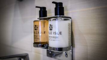 Two toiletry bottles mounted on a wall in a bathroom.