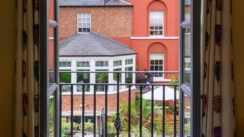 A room with a view of a red brick building through a window with curtains.