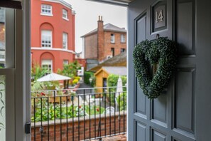 A view from a balcony with a black door, a heart-shaped wreath, and a red building in the background.