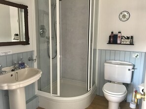 Une salle de bain avec une douche  à parois de verre, un lavabo blanc et des toilettes.