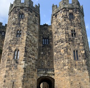 Un château historique en pierre, doté de deux hautes tours, de fenêtres en arc et d’une entrée centrale.