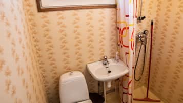 Ein Badezimmer mit Toilette, Waschbecken, Dusche und einem Fenster über dem Waschbecken.
