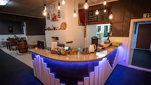 A bar area with a counter, bar stools, a coffee machine, and various bottles. - Arctic Guesthouse & Igloos (Ranua)