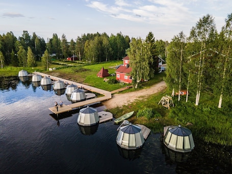 A lakeside property with several dome-shaped structures, a wooden dock, and a red house.