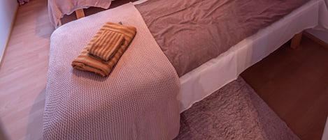 Une chambre avec deux lits simples, une fenêtre avec des rideaux, un tableau au mur et une lampe suspendue.
