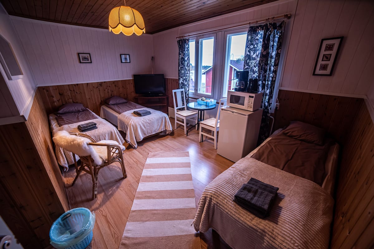 Ein gemütliches Zimmer mit zwei Einzelbetten, einem kleinen Tisch mit Stuhl, einem Fernseher und einer Mikrowelle.
