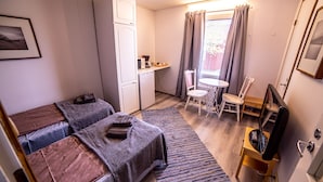 A compact room with two beds, a small kitchenette, a dining area, and a TV. - Arctic Guesthouse & Igloos (Ranua)