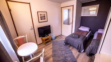 A hotel room with a bed, a television, a small table, and a chair.