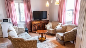 A living room with a sofa, two armchairs, a coffee table, a television, and a microwave. - Arctic Guesthouse & Igloos (Ranua)