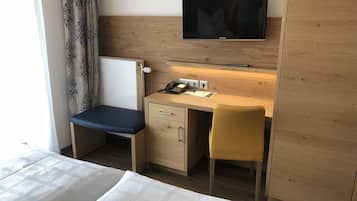 Een hotelkamer met een bed, een bureau met stoel, een televisie en een nachtkastje.