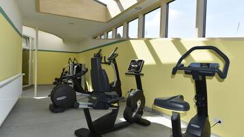 A gym with exercise equipment, large windows, and a skylight.