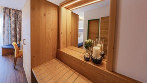 Un tocador de madera con un espejo, un banco y una mesita con velas y flores.
