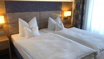Quarto de hotel com uma cama grande, duas mesas de cabeceira e uma cabeceira com painel texturizado.