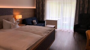 Una habitación de hotel con una cama grande, un escritorio, una silla y un sofá.