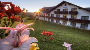 Un hotel con fachada blanca, balcones y un césped bien cuidado.