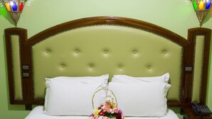 A neatly made bed with white linens, a floral arrangement in a basket, and a bedside telephone. - Hôtel Résidence Amalou (Marrakech)