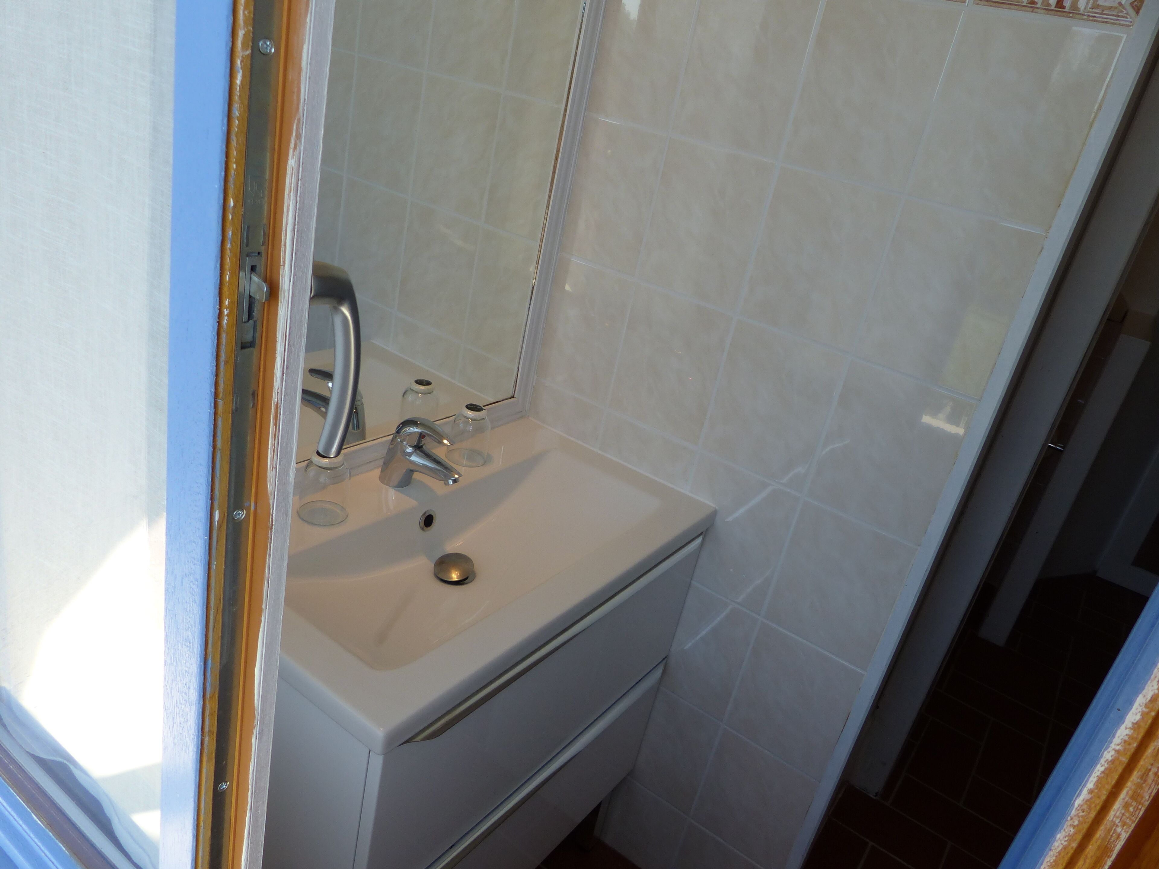 Ein Badezimmer mit einem weißen Waschbecken, einem Spiegel und einer Duschkabine.
