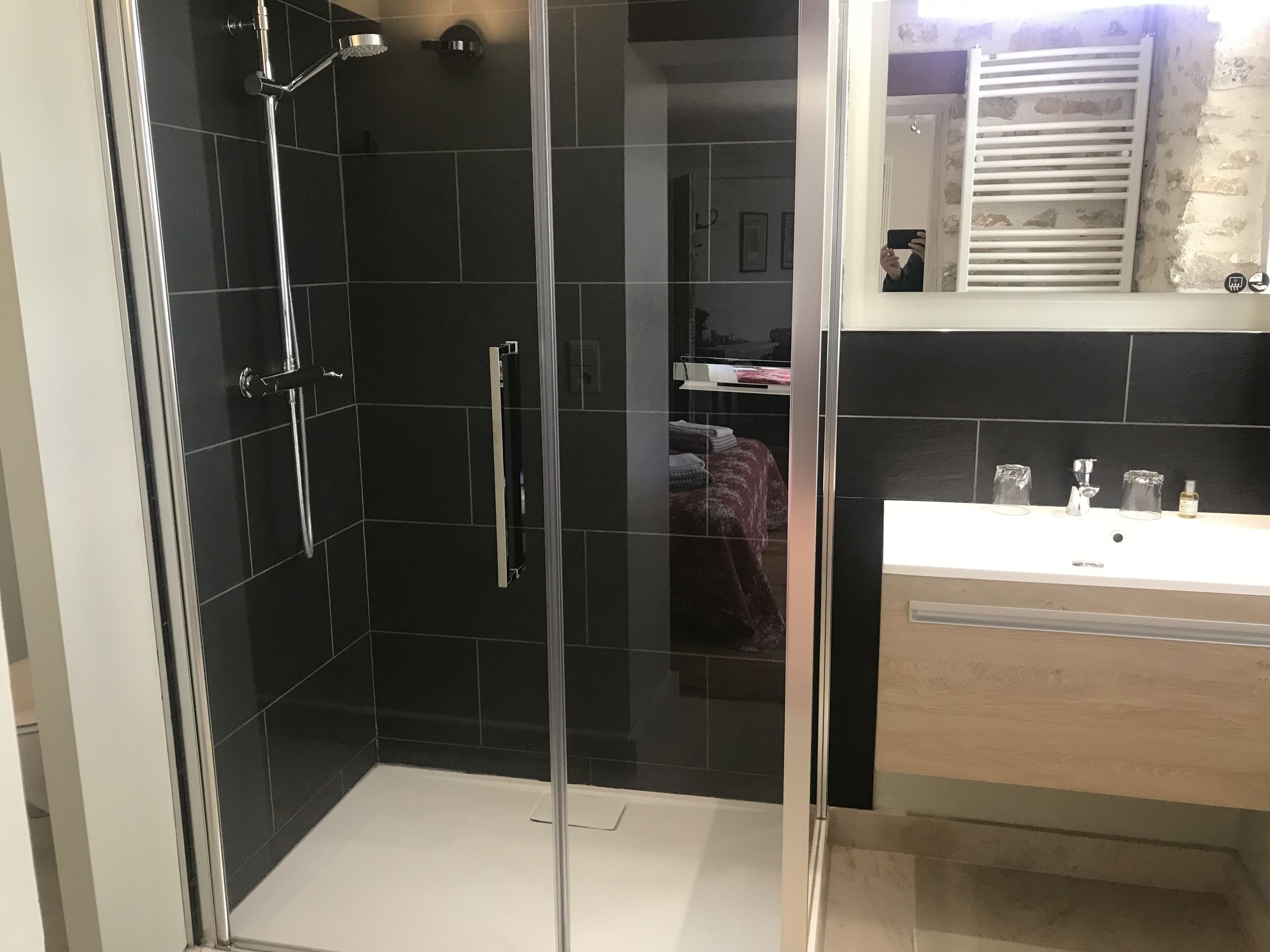 A modern bathroom with a glass-enclosed shower, a white sink, and a mirror with a towel rack.