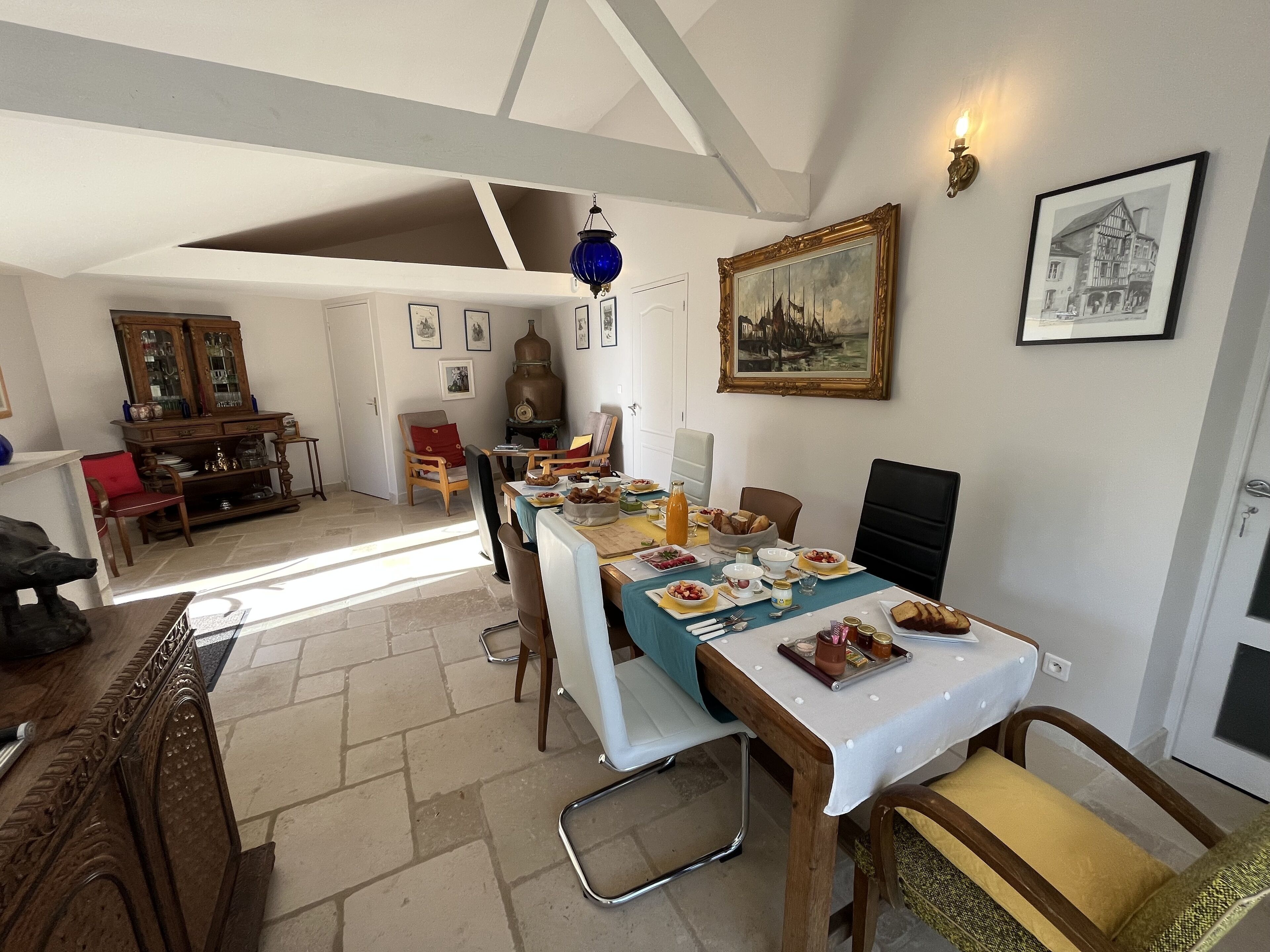 Un coin repas avec une table mise pour le repas, un buffet en bois et un luminaire suspendu bleu.