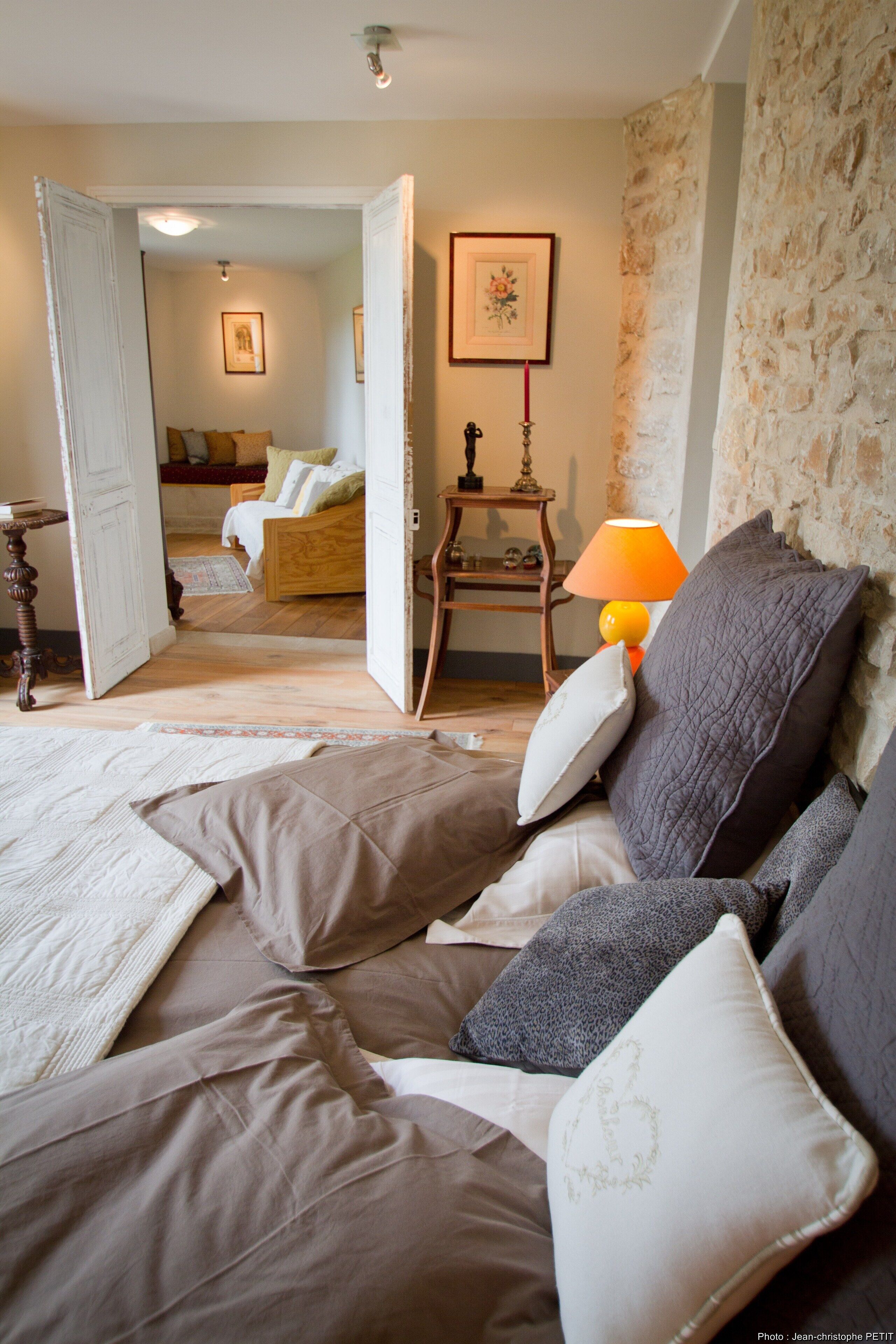 Een gezellige slaapkamer met een bed, kussens, een nachtkastje en een lamp.